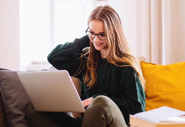 Woman with glasses typing on open laptop