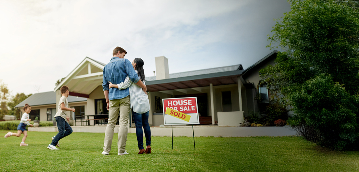 Family of four outside of new home with sold sign