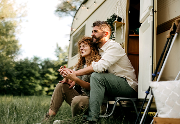 couple sitting on step in front of an RV