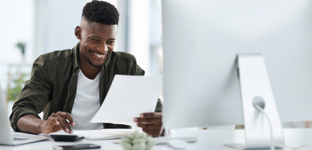 Man typing on calculator while holding piece of paper
