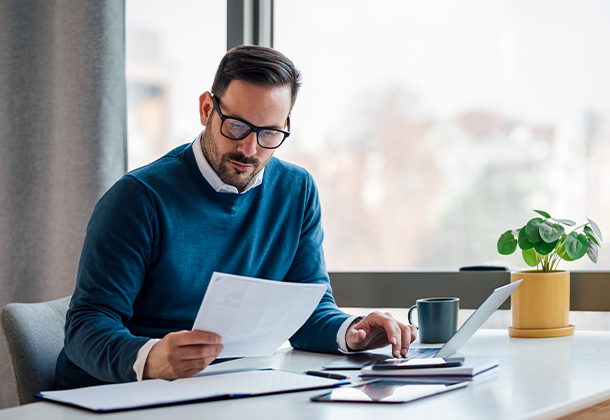 person reviewing piece of paper while typing