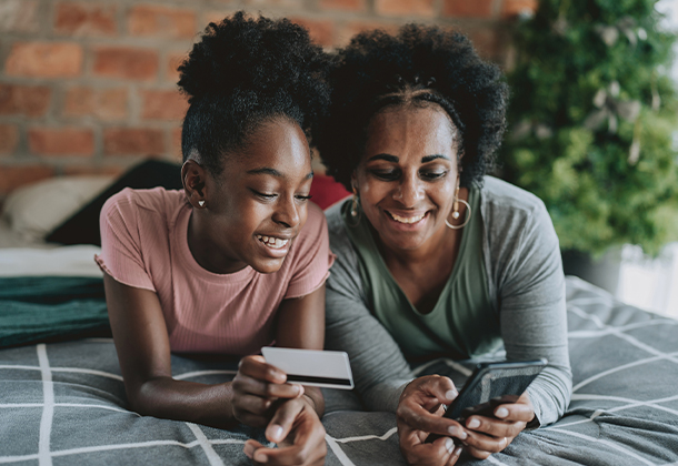 Two family members holding credit card and cell phone while smiling